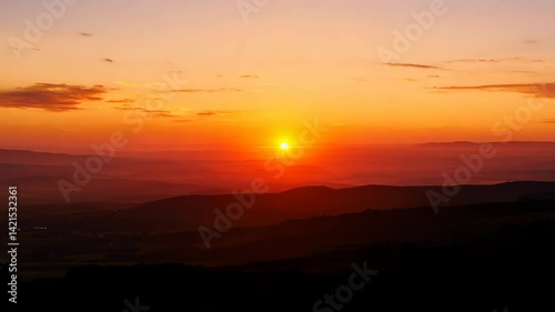 The beautiful sky displays colors of orange and red as the sun rises and sets over the majestic mountains, a stunning nature landscape
