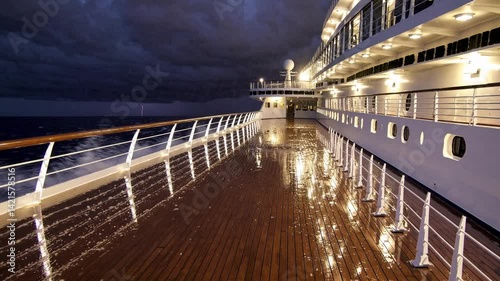 Dramatic cruise ship deck at night with stormy skies reflected on wet surface