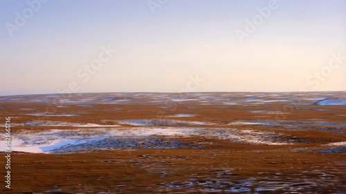 Serene Winter Landscape Patches of Snow on Brown Grassland Under a Pale Sky
