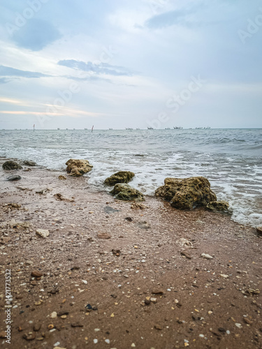 Tranquil Rocky Seaside with Overcast Sky and Gentle Waves