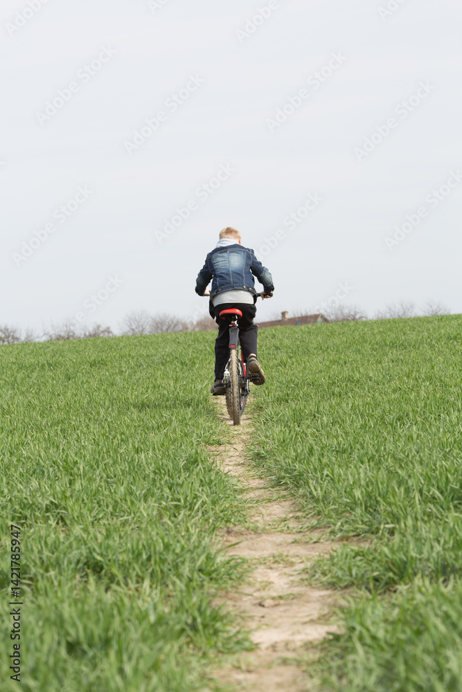 boy rides a bicycle across a field to his house boy rides a bicycle across a field to his house