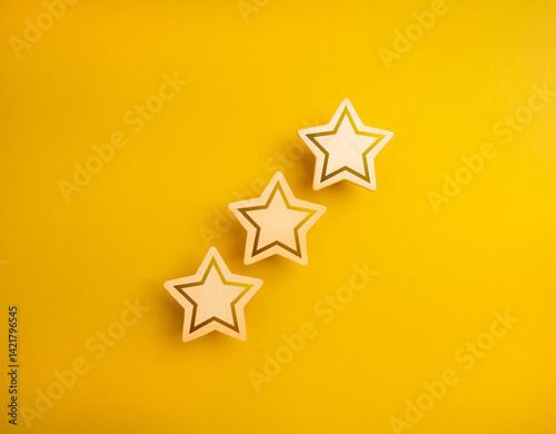 Shining three wooden stars ratings, isolated on yellow background, minimal style. High level of excellence quality or satisfaction, customer evaluation and review, business marketing concept.