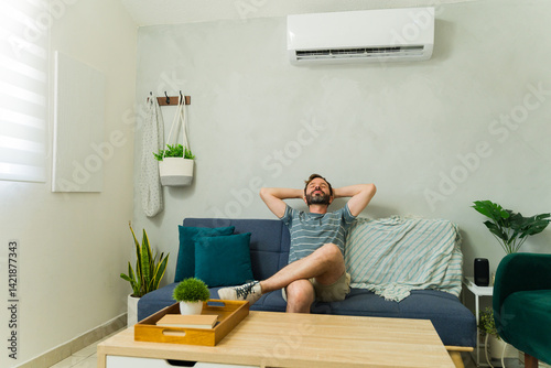 Obraz na płótnie Happy Caucasian man relaxing on sofa under air conditioning unit at home w salonie