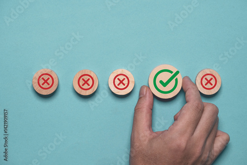 Hand holding green correct sign mark among Red Cross mark for business project approval and document approve concept.
