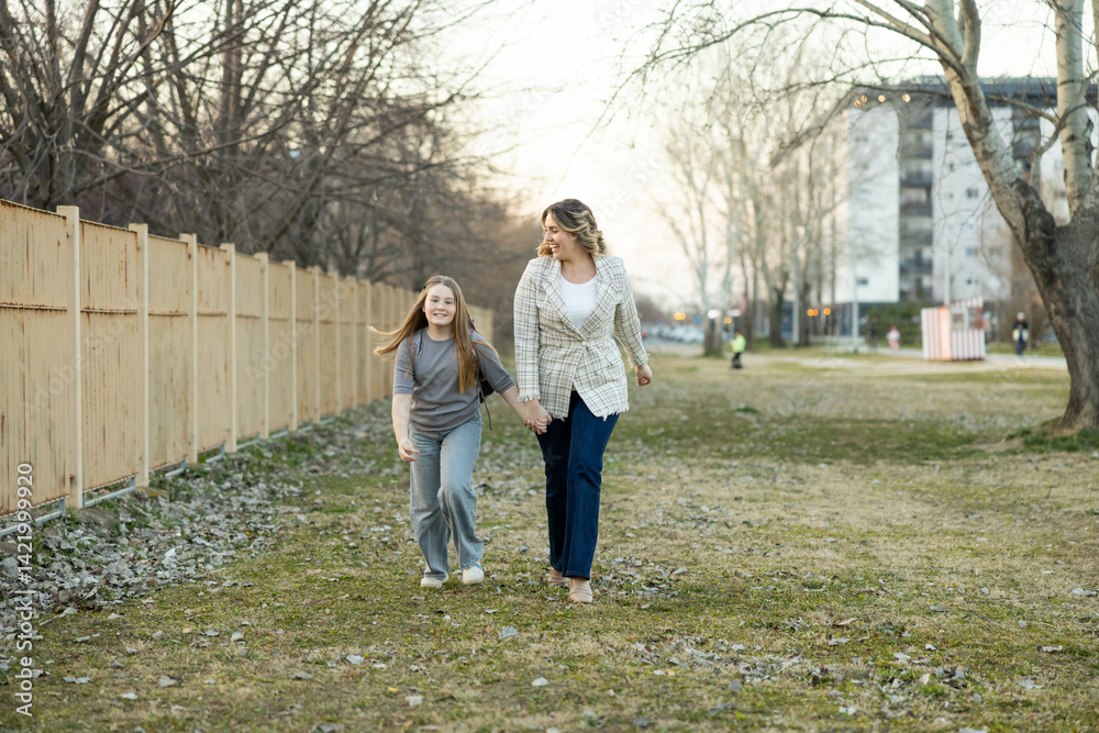Fototapeta premium A mother and daughter walk hand in hand, filled with laughter and joy as they embrace their outdoor adventure together.