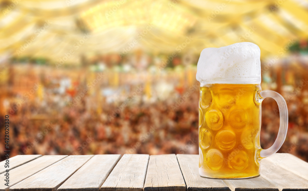 Fototapeta premium Mug of beer on wooden table on tent beer background. Oktoberfest, beer festival