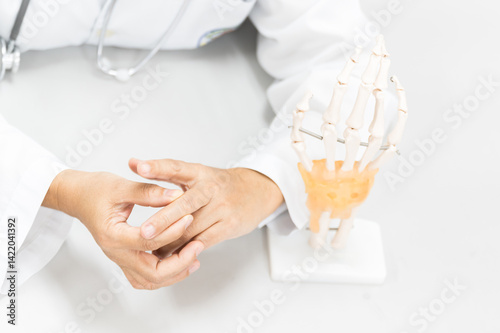 Orthopedist explain to the patient for human hand and fingers bone injury treatment program.Doctor showing to finger bones anatomy to gout patient.Physiotherapy present hand model for injured athlete.