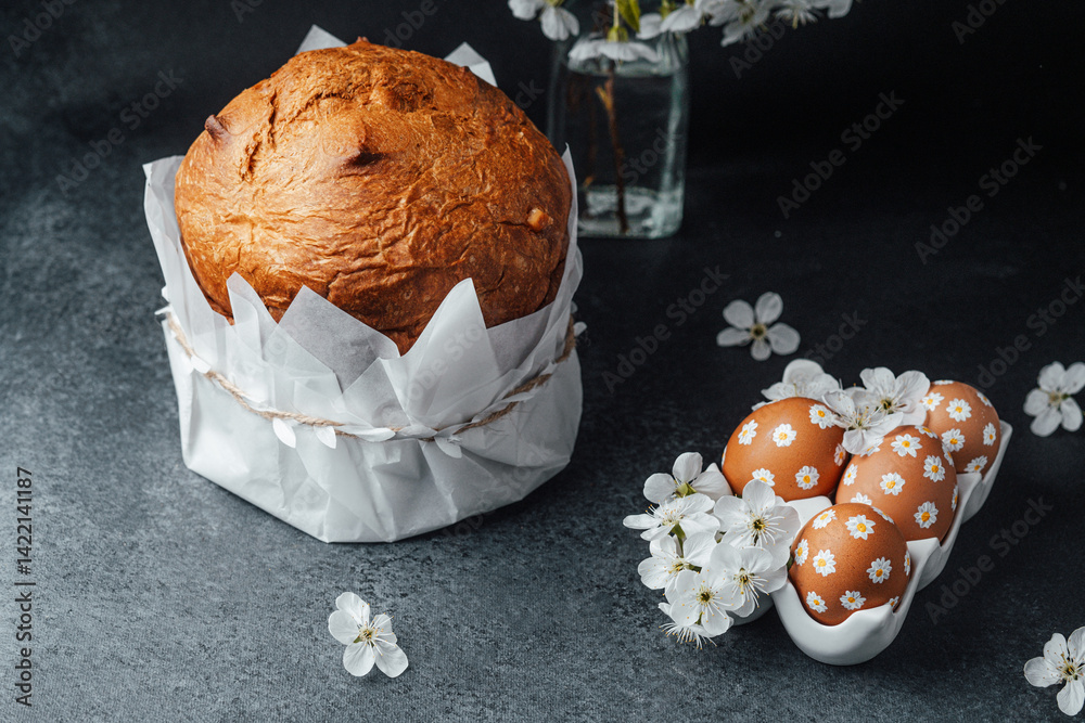Delicious Easter bread and decorated eggs on a dark tabletop with flowers