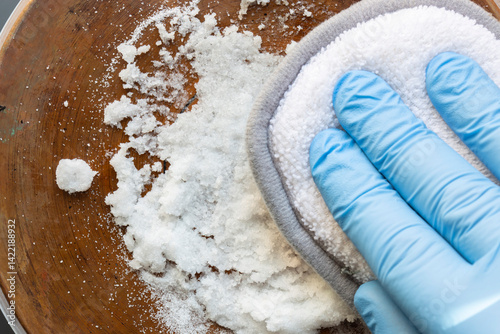 Canvastavla Person cleaning a copper base of a saucepan using bicarbonate of soda and a scouring pad
