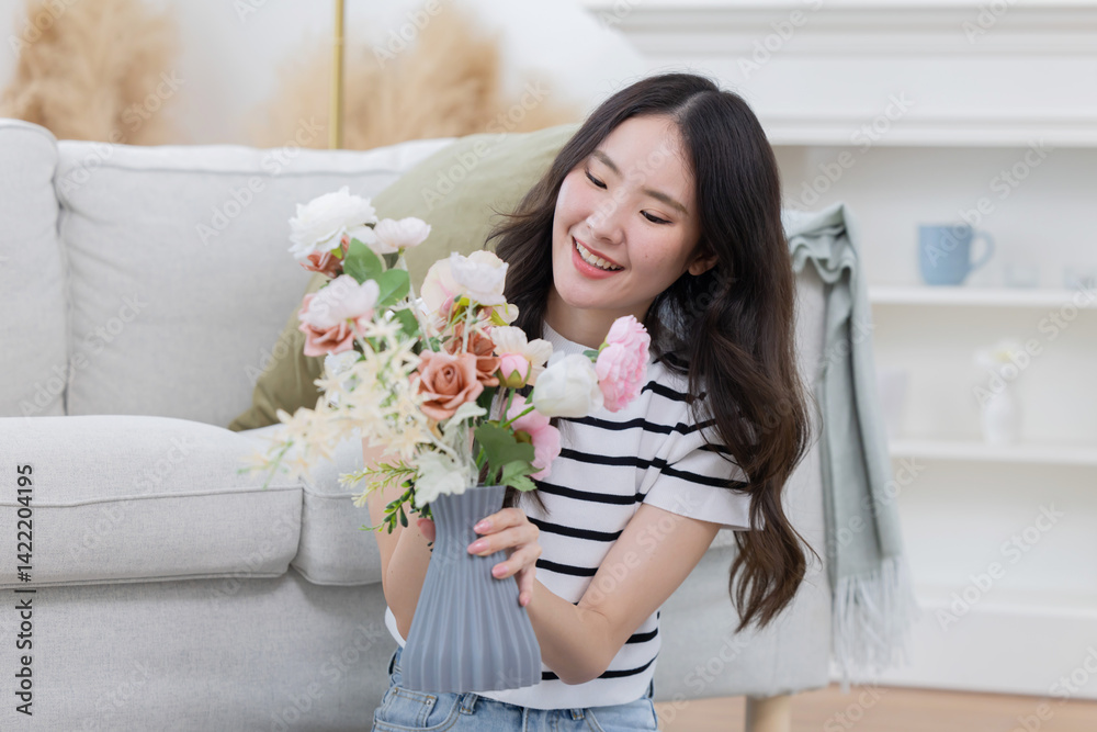 Young asian woman arrange flowers in a vase in a living room Young asian woman arrange flowers in a vase in a living room
