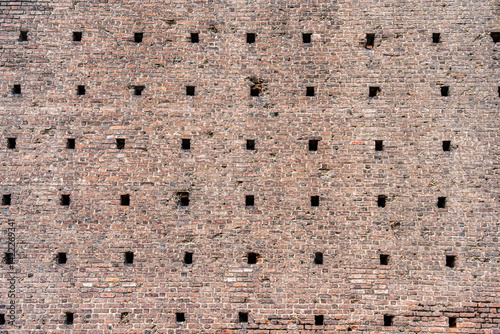 A close-up view with the medieval brick wall part of the historic Sforza Castle (Castello Sforzesco) in Milan, Italy. Brick wall background texture.