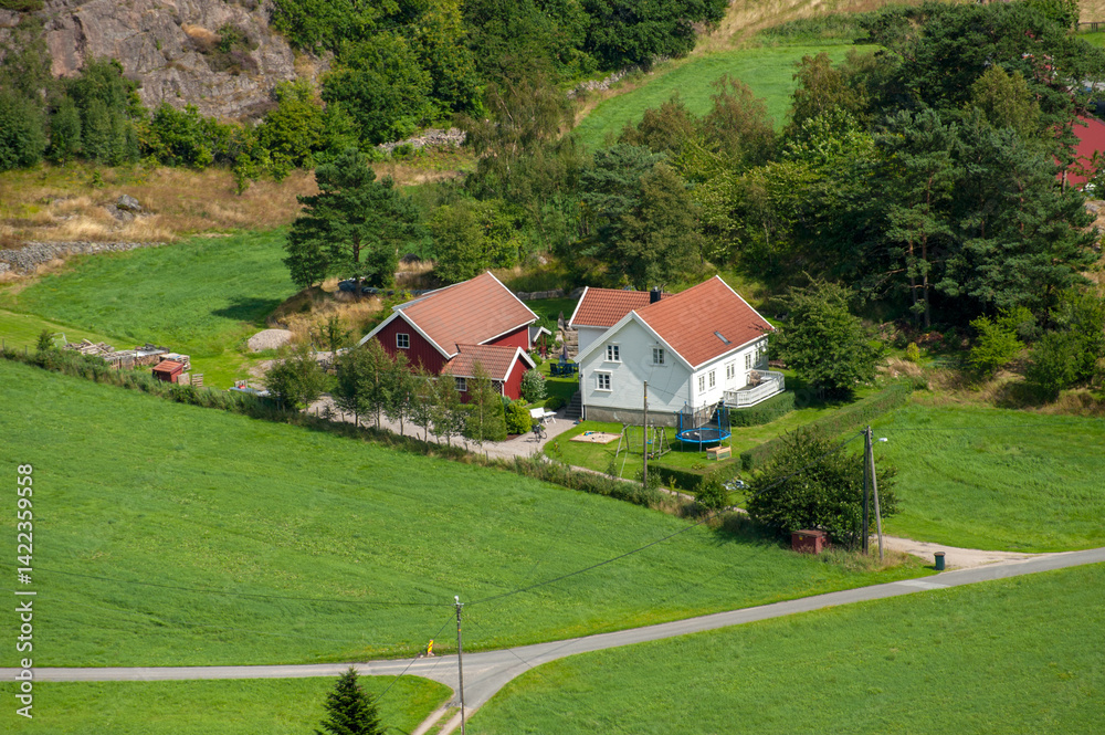 Aerial view of red-roofed house in green valley. Aerial view of red-roofed house in green valley.