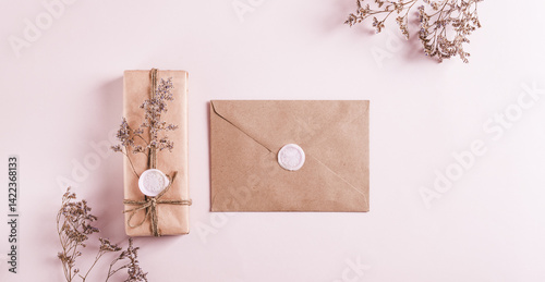 Obraz na płótnie Gift in kraft paper and envelope with wax seals and dried flowers on pink top view web banner w salonie