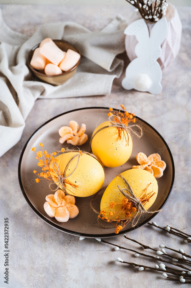 Easter eggs decorated with dried flowers and marshmallows on a plate on a table vertical view