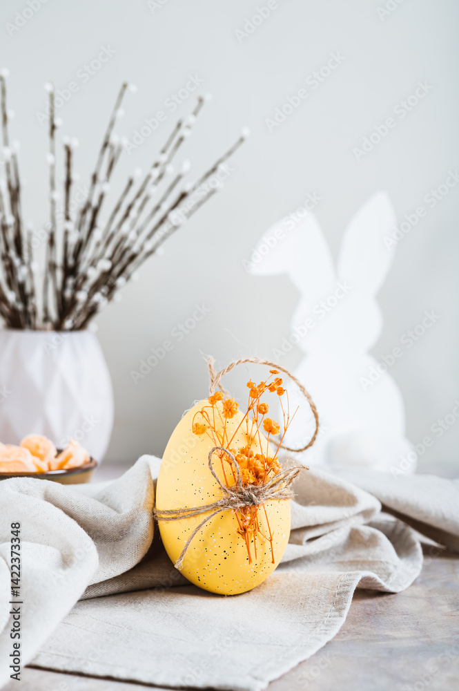 Easter decorated egg on fabric, bunny and willow on table vertical view