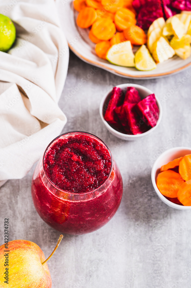 A glass with a mixture of beetroot, apple and carrot juices ABC on the table vertical view