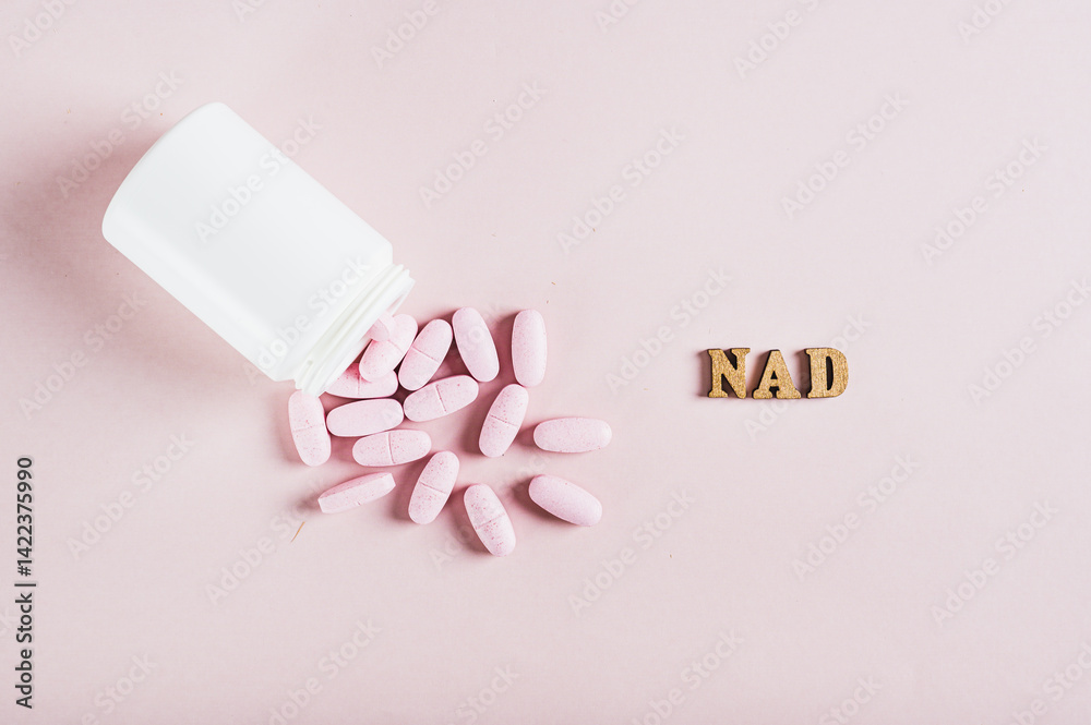 Close up of nicotinamide adenine dinucleotide anti-aging pills and a bottle on pink top view