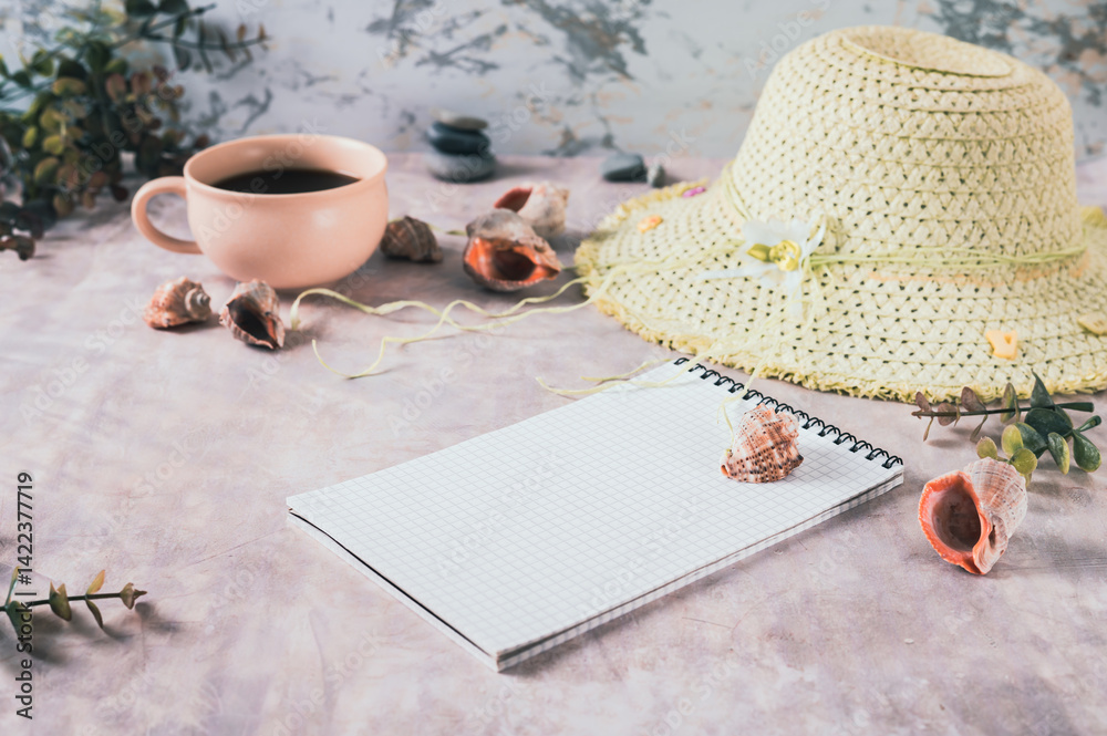 Notebook, beach hat, shells and stones on the table