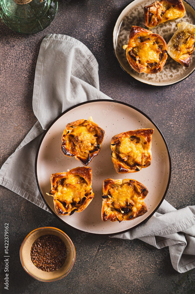 Homemade caramelized onion savory pies on a plate on the table top and vertical view
