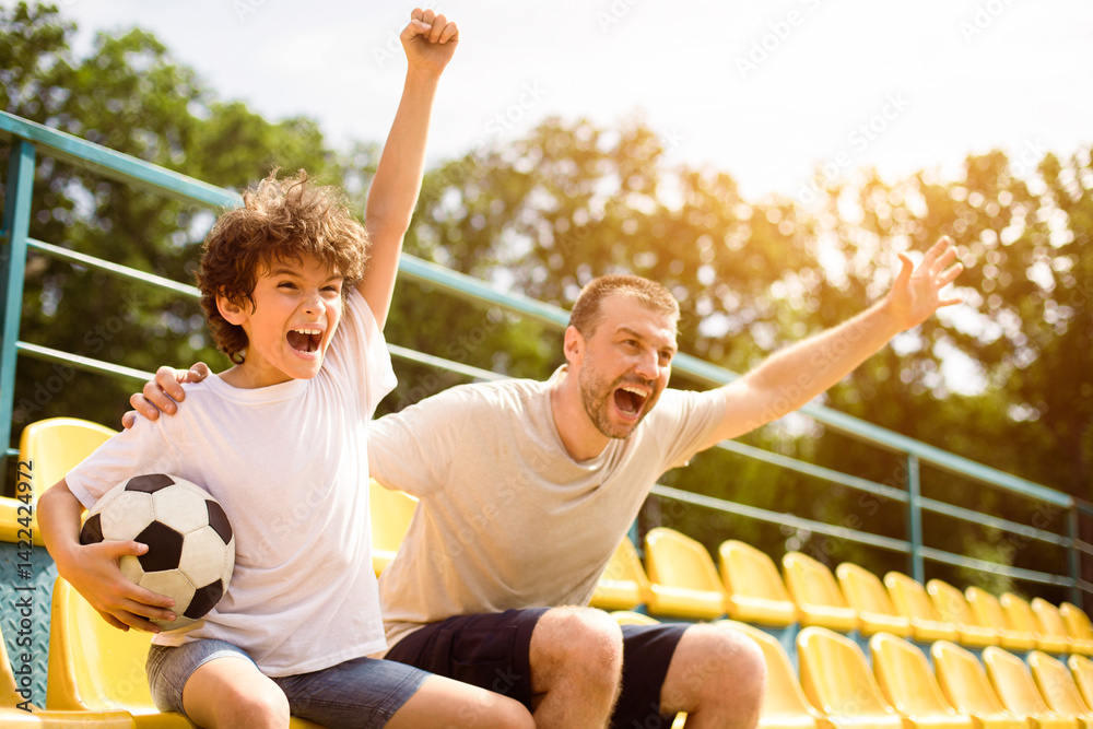 Obraz premium Goal. Emotional man and little boy cheering their favorite team, little boy holding soccer ball