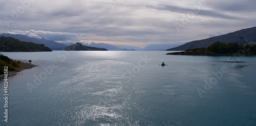 Sunset on a lake. Fishing boat at sunset in Patagonia, Chile. Beautiful summer landscape. Calm windless weather, heavy clouds.