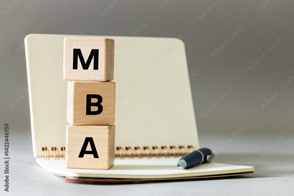 MBA symbol. Word Master of Business Administration on wooden blocks on table with notebook and pen on gray background. copy space