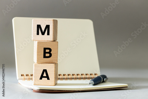 Obraz na płótnie MBA symbol. Word Master of Business Administration on wooden blocks on table with notebook and pen on gray background. copy space w salonie