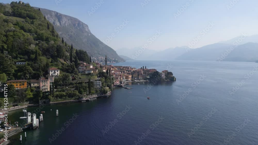 Aerial orbit view of Varenna during sunny afternoon from far, famous picturesque old town and turistic destination in Lake Como, Lombardy, Italy. Lake and mountains behind. Cinematic 4K drone shot. Aerial orbit view of Varenna during sunny afternoon from far, famous picturesque old town and turistic destination in Lake Como, Lombardy, Italy. Lake and mountains behind. Cinematic 4K drone shot.