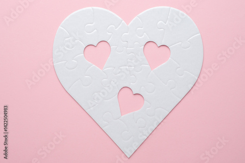 White heart-shaped jigsaw puzzle on a grey background, with several pieces missing and placed nearby. Symbolizing love, connection, or incompleteness, perfect for themes of relationships and emotions.