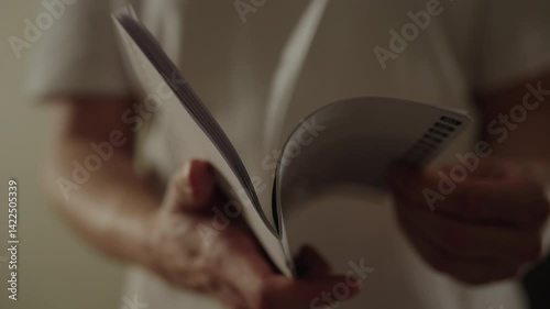 Close-up view of male hands turning pages of instruction manual, engaging in reading and absorbing new information. Repairman leafing through instruction manual, studying details indoors, slow motion.