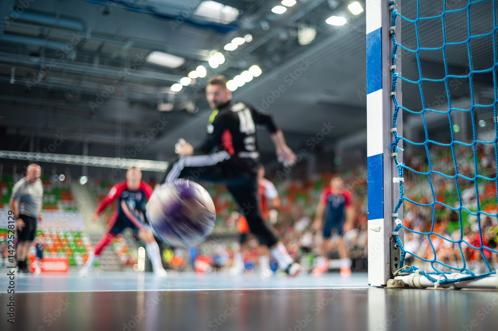 Detail of handball goal post with net and handball match in the background..handball;