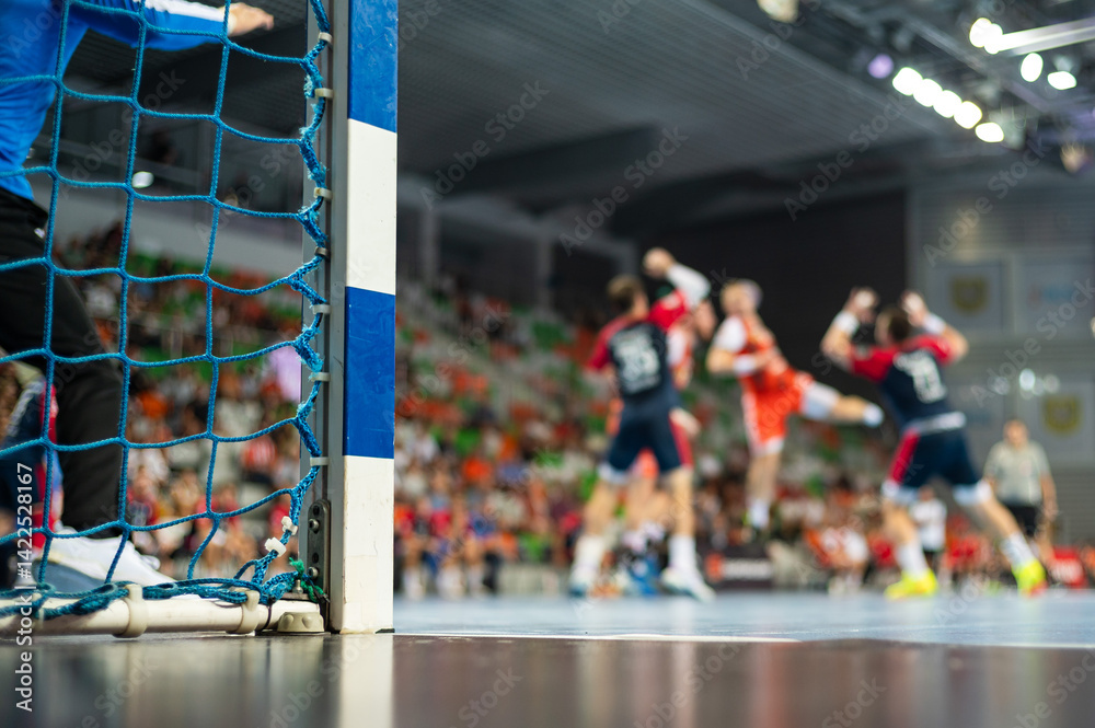 Detail of handball goal post with net and handball match in the background..handball;