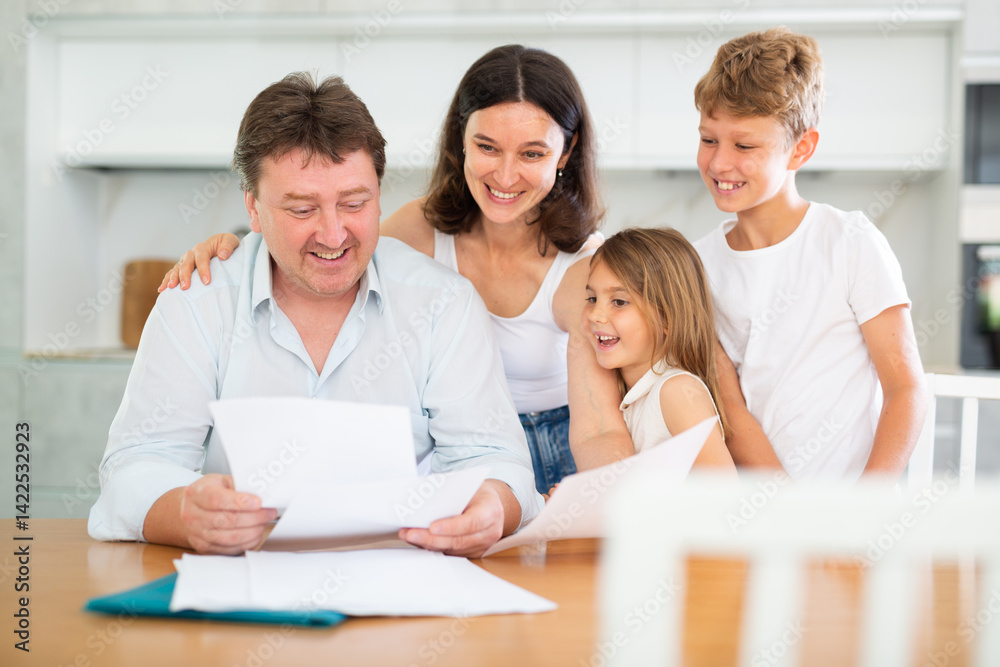 Happy satisfied family reading documents together while sitting at the table at home