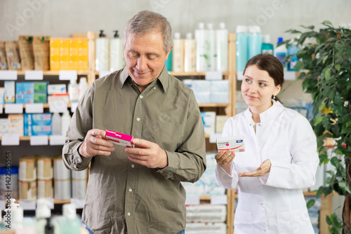 Obraz na płótnie Elderly man chooses pills in modern pharmacy. Female pharmacist helps with choosing a medicine w salonie