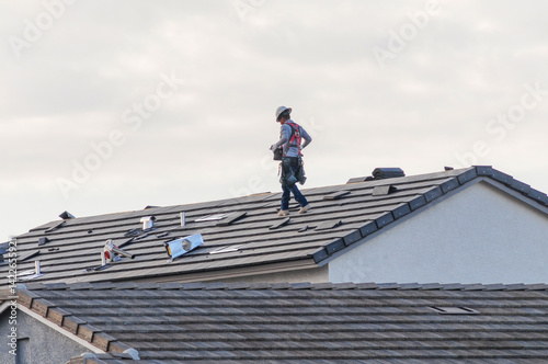 Принти на полотні A roofer in a safety harness walks across the pitched roof of a newly constructe