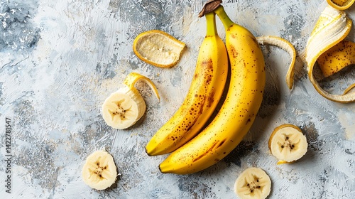 Fresh Yellow Bananas with Slices and Peels on Gray Background