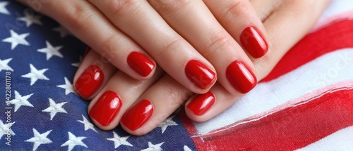 A close-up of manicured hands with red nail polish resting on an American flag, symbolizing patriotism and style.