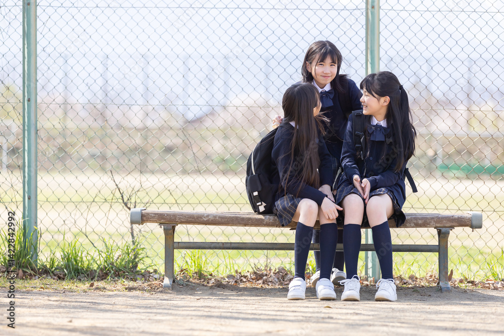 グラウンドのベンチに座る女子学生