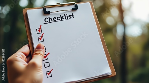 A hand holds a clipboard upright featuring a checklist for review. photo