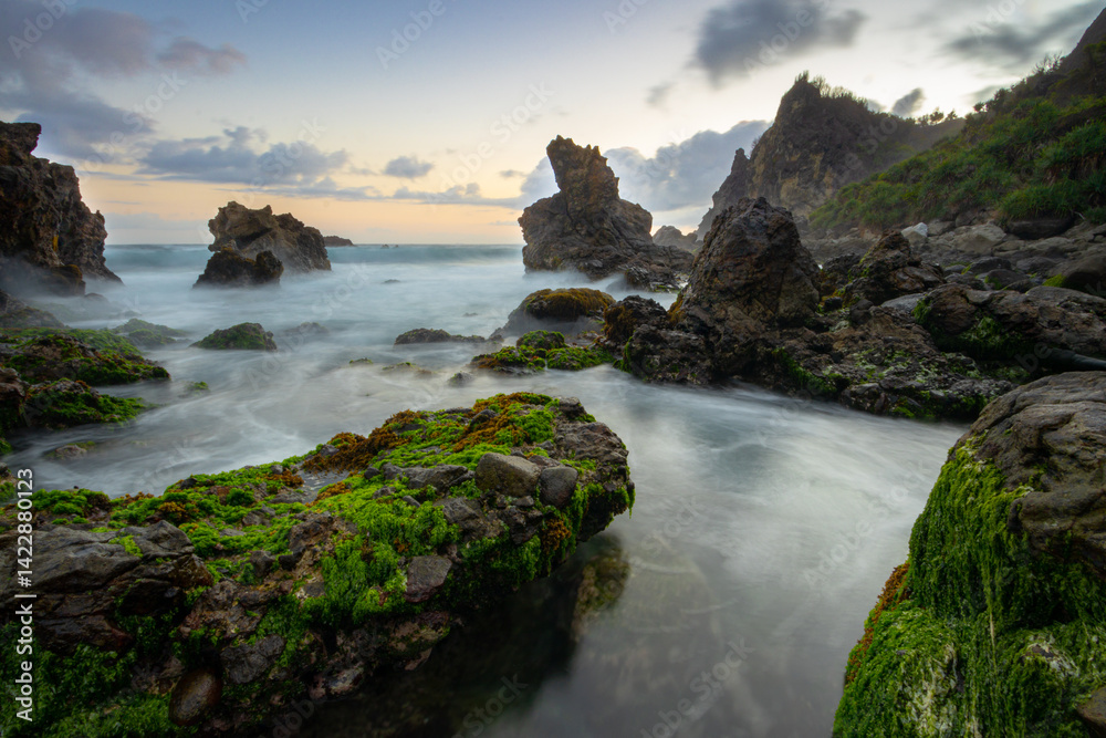 Obraz premium The twilight at Watu Lumbung Beach presents its own charm, with the dimming sunlight and the sound of thunderous waves crashing against the coral rocks.