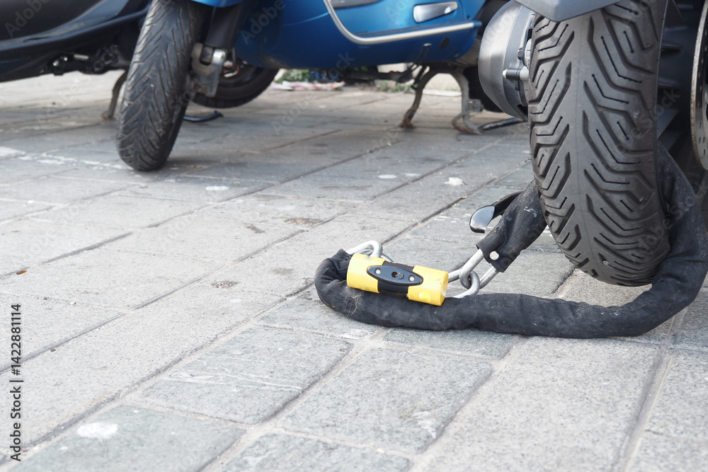 Fototapeta premium Motorcycle secured with a lock on a city street during daytime