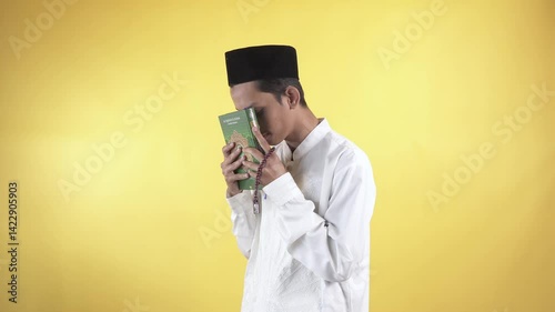 Footage of muslim man wear white shirts with Islamic ornaments close the quran then pay homage to Holy book of Quran