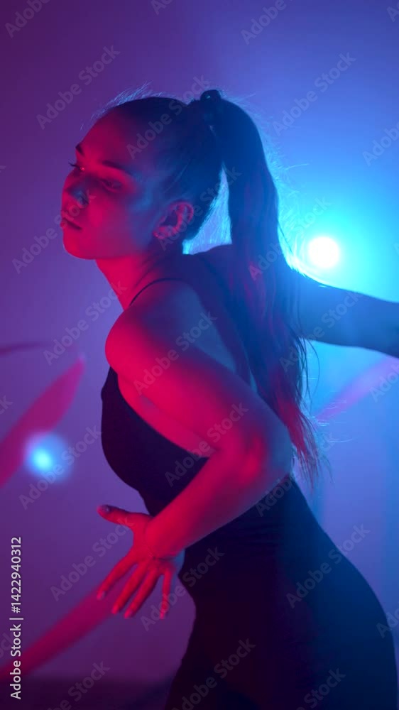 Female gymnast performs rhythmic gymnastics with ribbon under neon lights Female gymnast performs rhythmic gymnastics with ribbon under neon lights