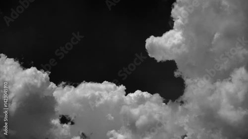 Time-lapse of separate white clouds on a black background has real clouds