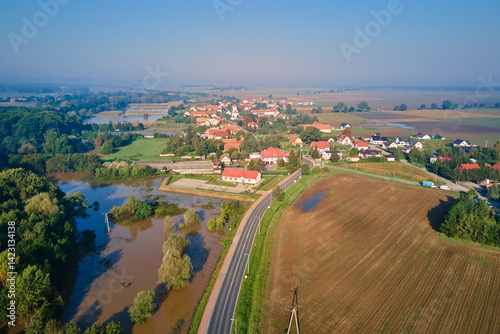 Aerial view of flooded landscape with rural village, farmlands and forest. Natural disaster