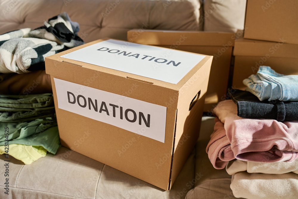 Donation boxes in living room. Packed cardboard boxes full of clothes and toys on couch. Concept of charity, social care and volunteering