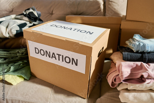 Obraz na płótnie Donation boxes in living room. Packed cardboard boxes full of clothes and toys on couch. Concept of charity, social care and volunteering w salonie
