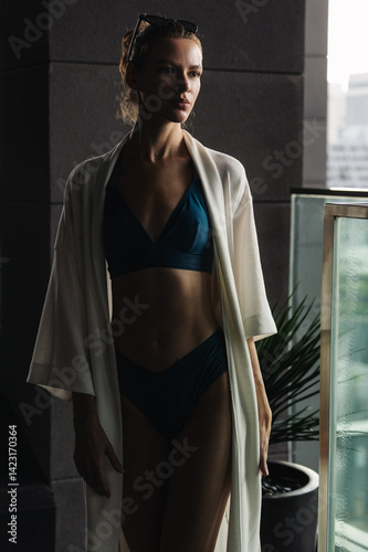 Tanned girl in swimsuit and robe on holiday in hotel. Cinematic evening light.