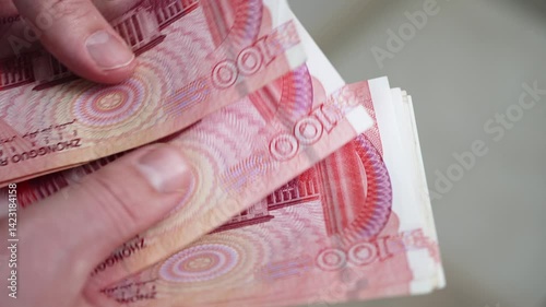 Businessman carefully counting chinese one hundred yuan banknotes, demonstrating financial expertise and meticulous attention to monetary transactions within global economic landscape