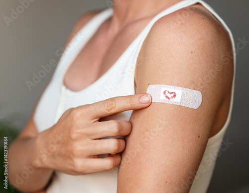 Foto Female pointing at adhesive bandage with drawn heart on her arm at vaccination site